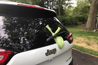 Dog poo bag hanging on a car's rear wiper.