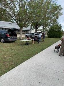 A group of people standing next to a sidewalk and a table

Description automatically generated